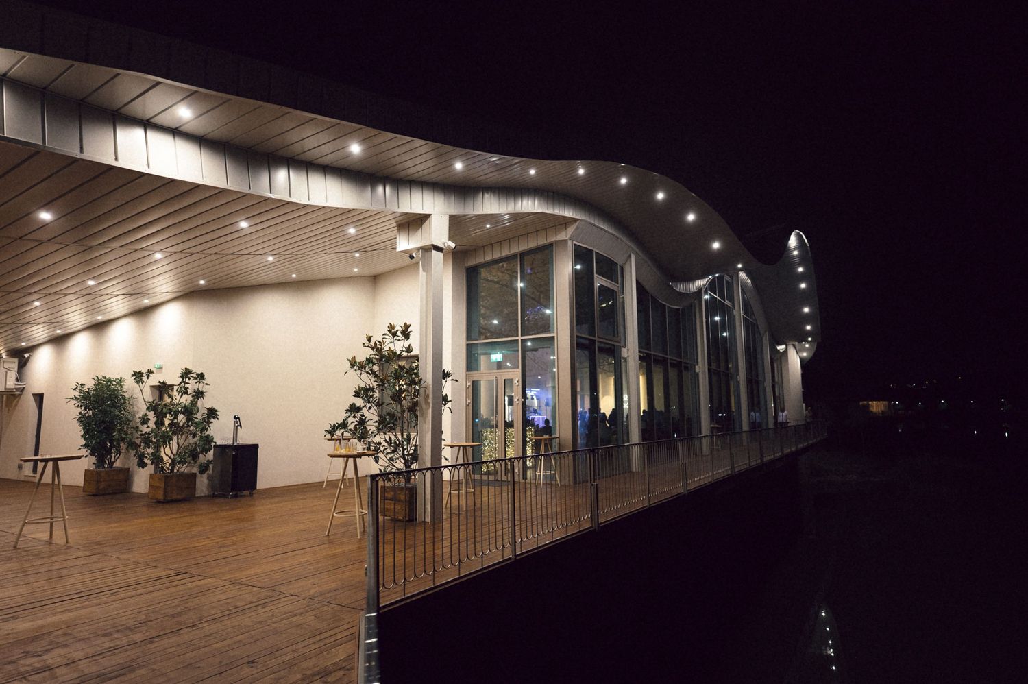 Dimly lit outdoor corridor with modern architectural lighting and glass panels creating an atmospheric nighttime scene.