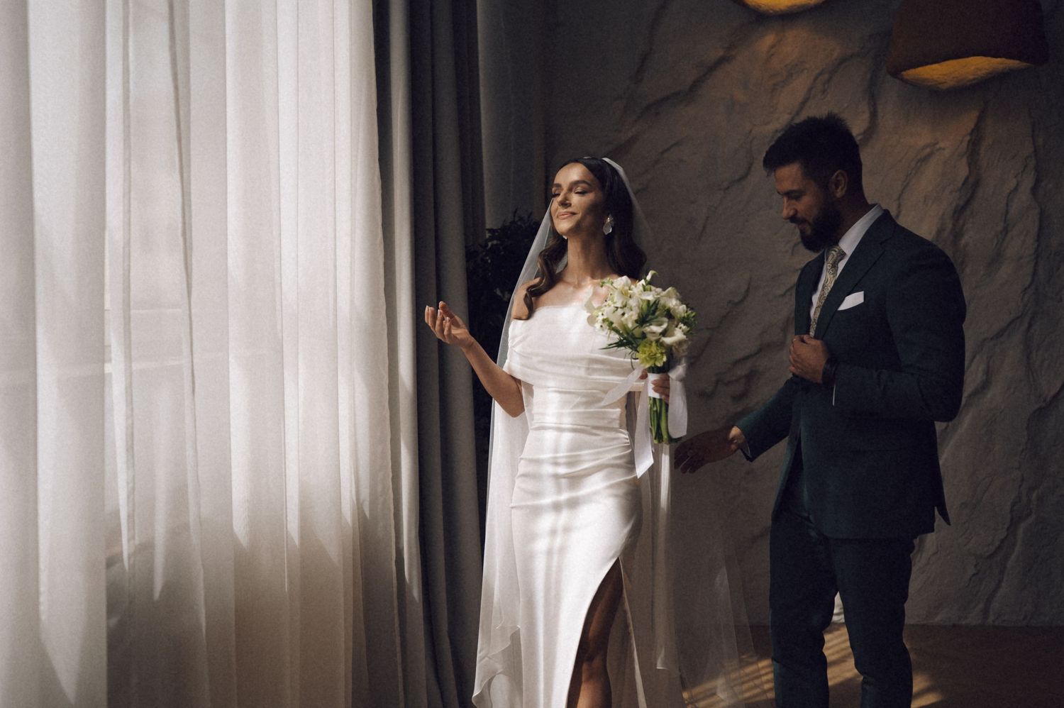 Bride and groom share a tender moment in front of white curtains during their wedding ceremony.