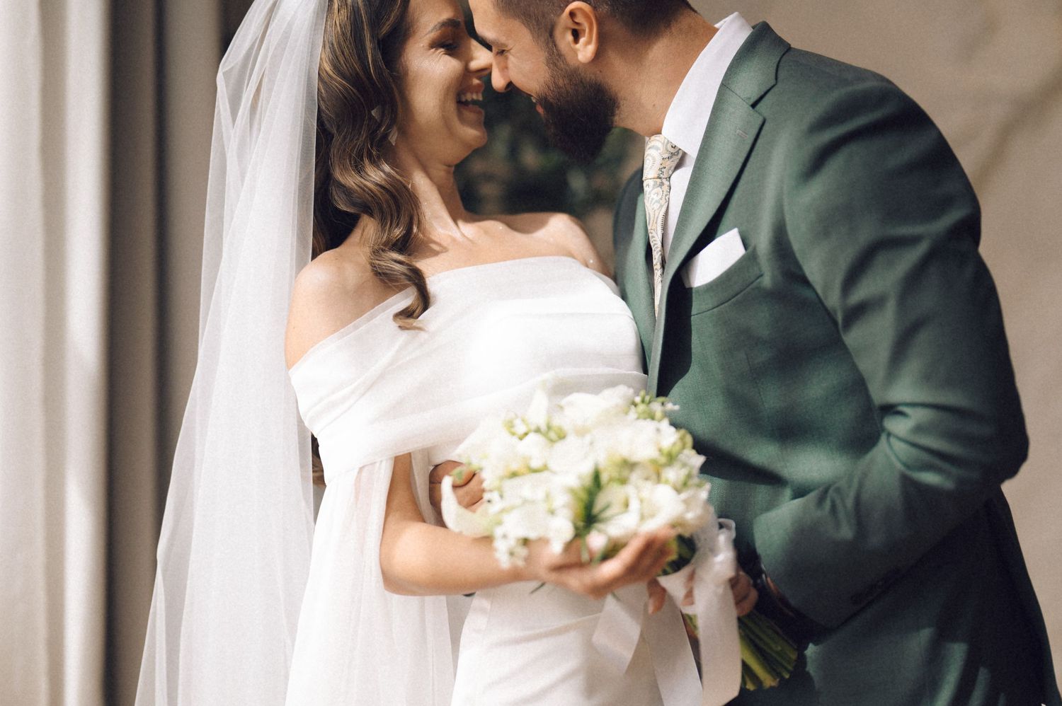 A bride and groom share an intimate moment together in an elegant hallway with white columns.