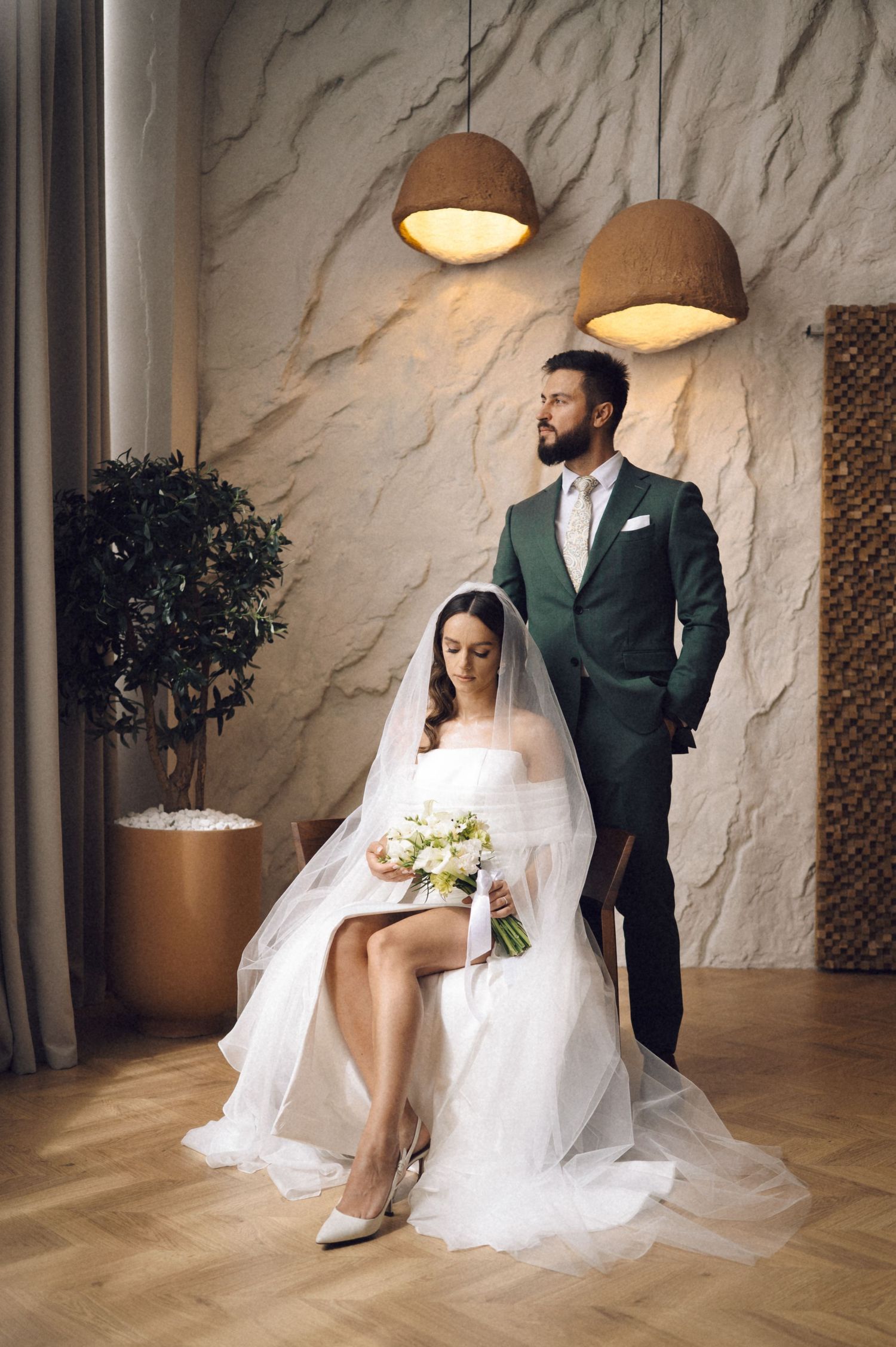 Wedding couple poses in a stylish modern interior with textured white walls and warm lighting in a series of photos.
