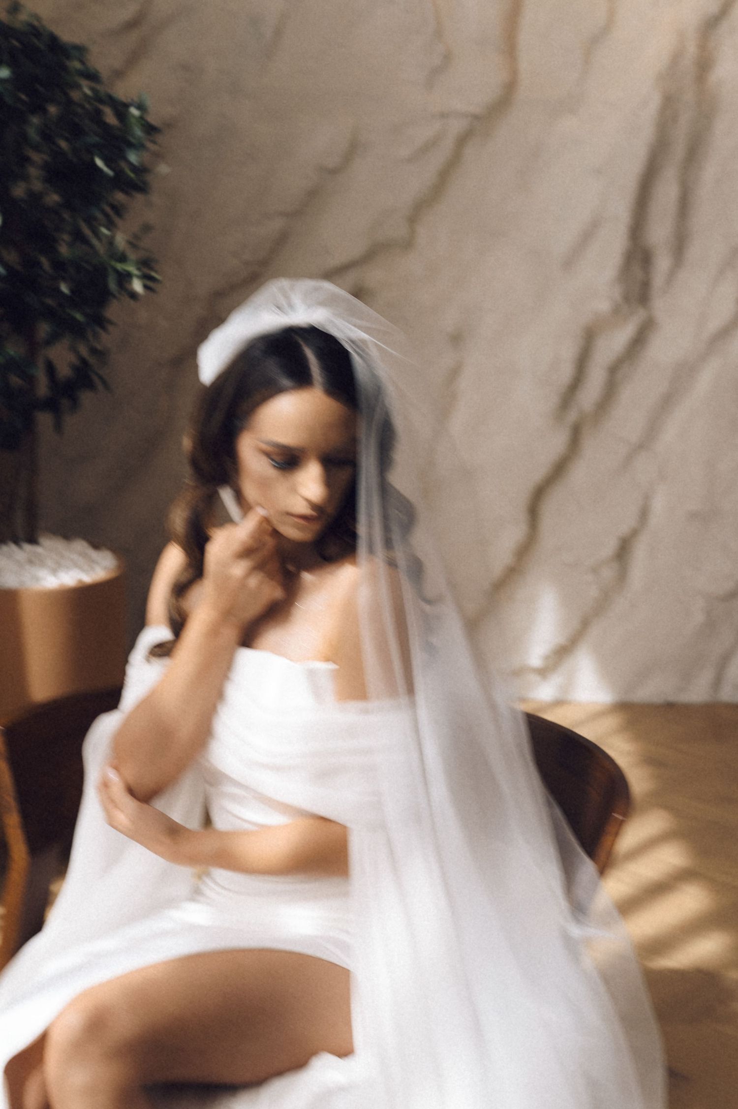 A series of artistic bridal portraits showing a person in a white wedding dress and veil against a textured beige wall.