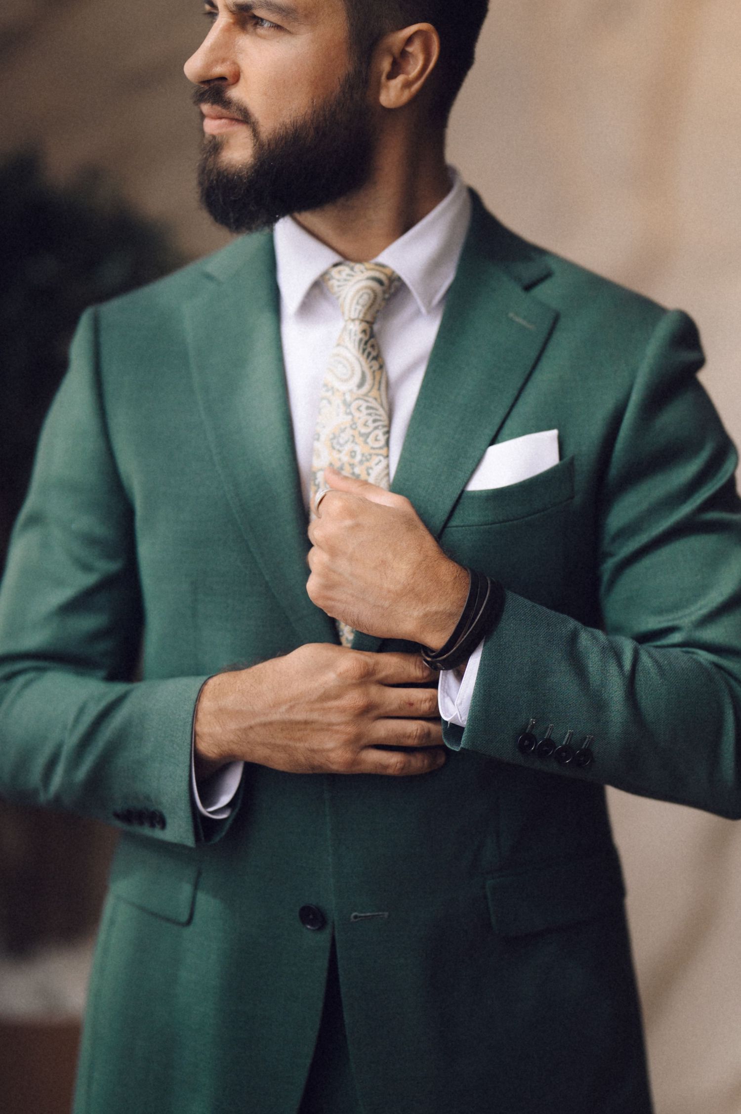 Close-up shots of a green suit jacket with white dress shirt and patterned tie being adjusted.