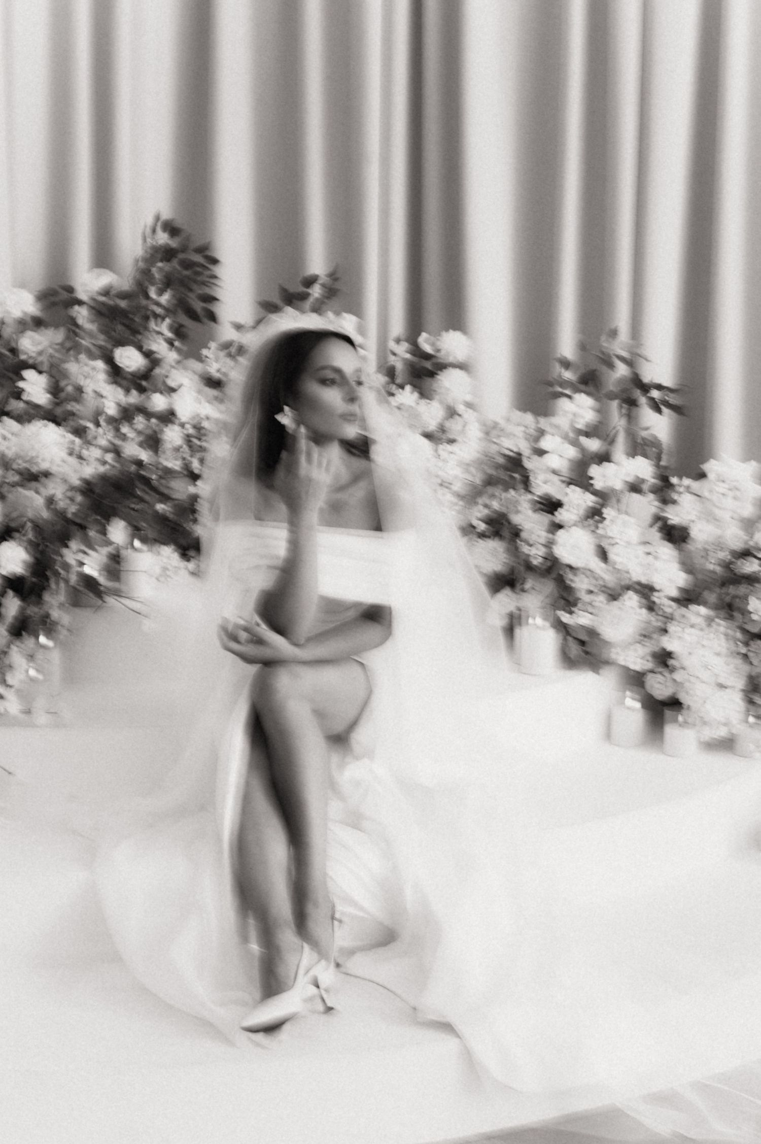 Artistic bridal portraits with flowing white dress and curtains creating ethereal motion effect.
