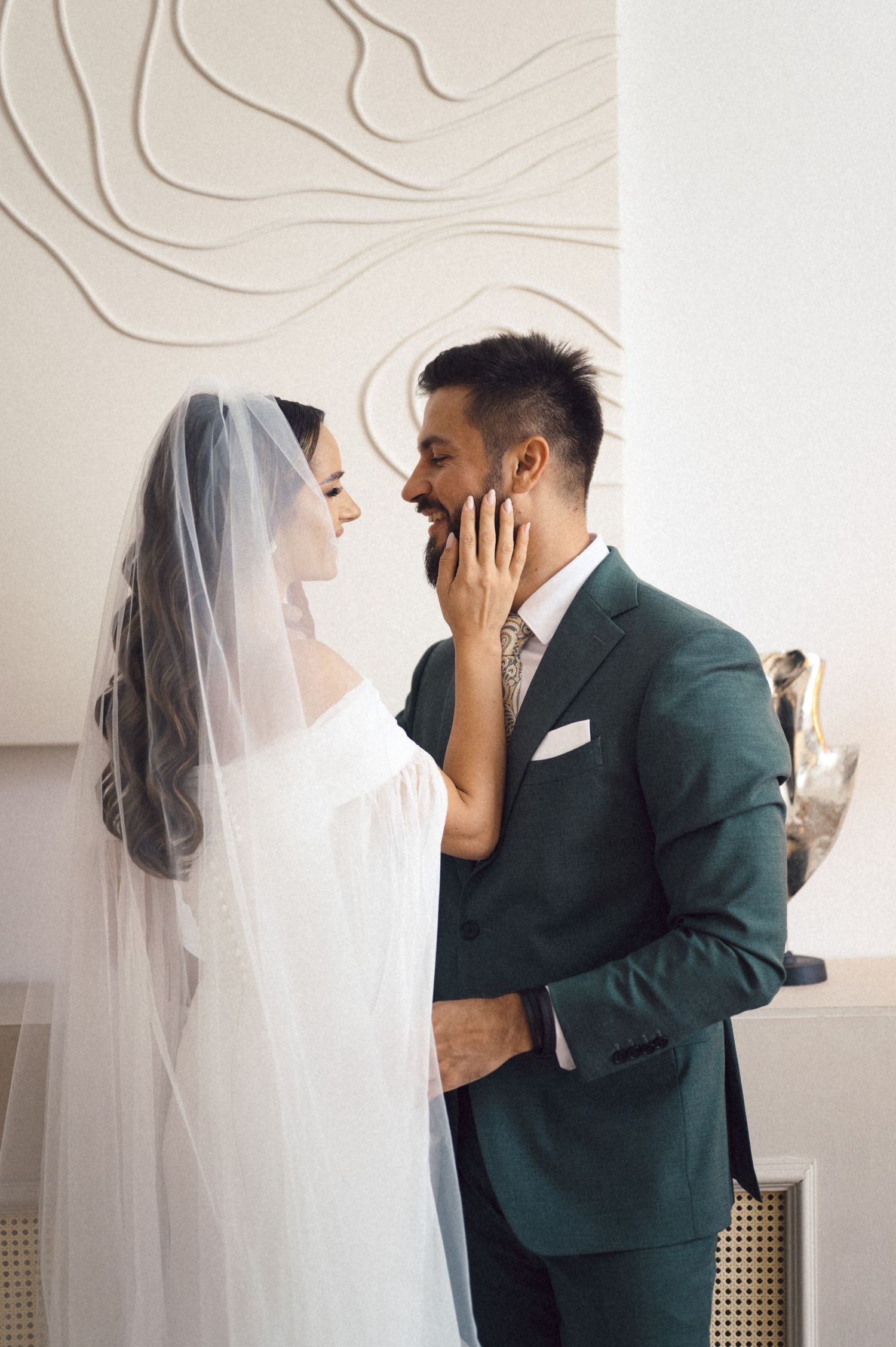 A series of intimate wedding moments showing a couple in a white dress and dark green suit embracing against a light background.