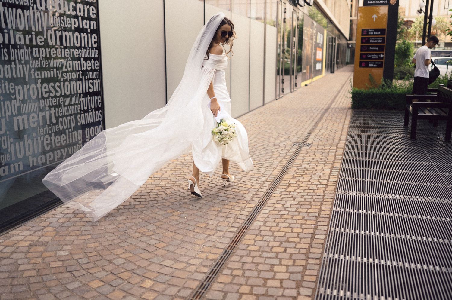 A bride in a flowing white dress walks down a modern architectural corridor with dramatic lighting and reflective surfaces.