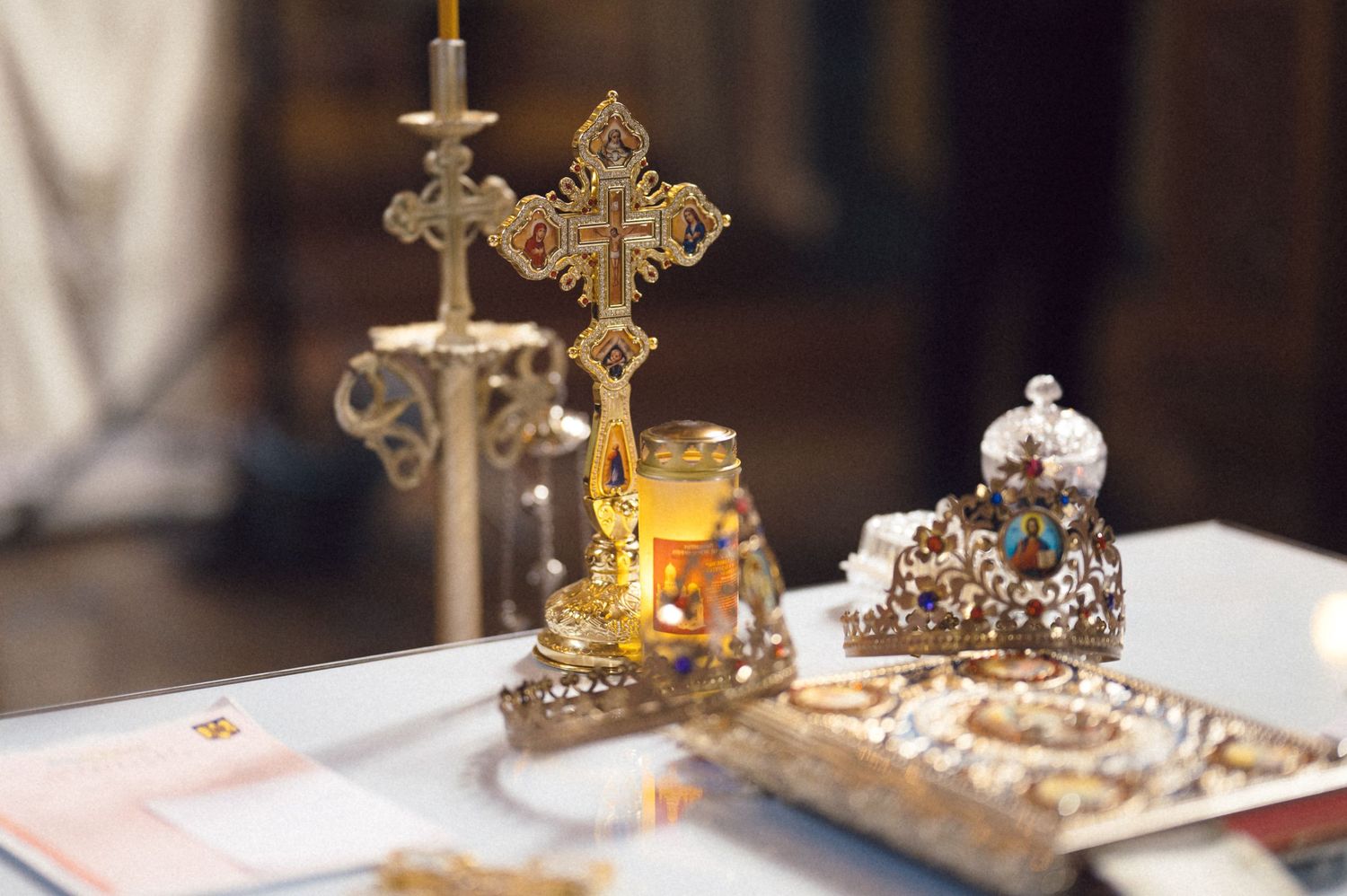 Ornate golden crowns and religious artifacts displayed on a ceremonial table during an Orthodox Christian wedding ceremony.