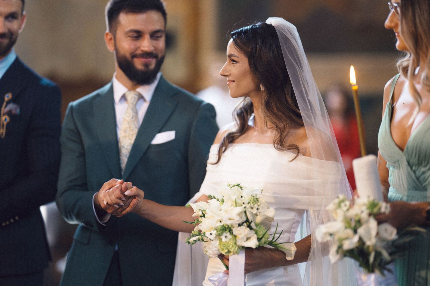 Couple shares an intimate moment during their wedding ceremony with candlelight and floral bouquets.