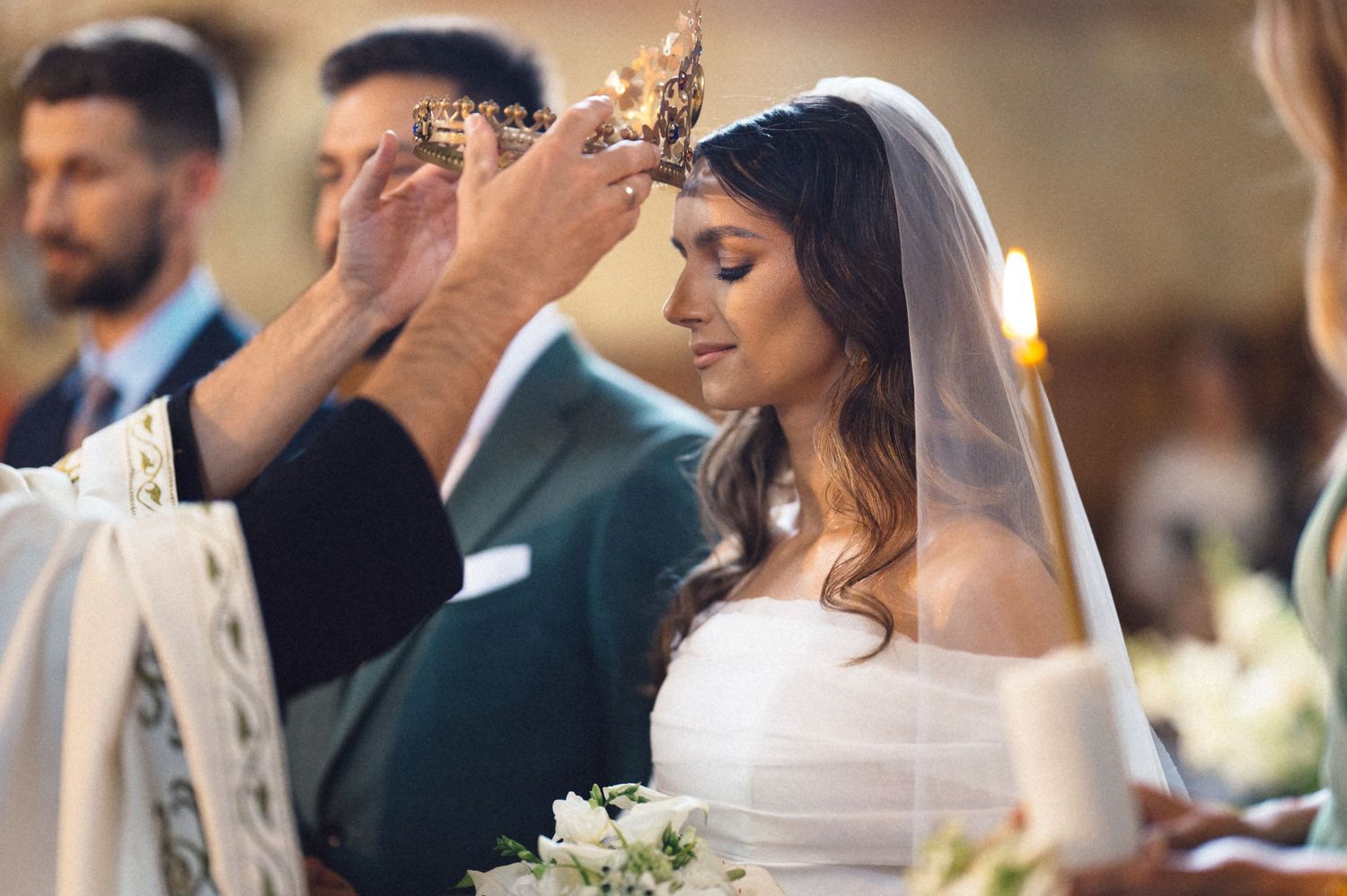 Close-up view of newlyweds during romantic candlelit wedding ceremony with white floral bouquet.