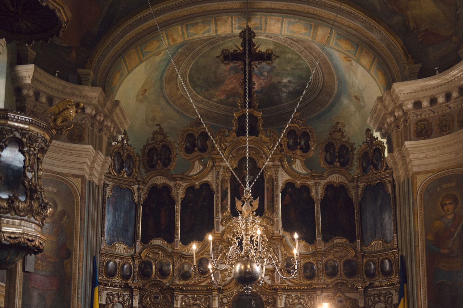 Ornate cathedral interior with grand chandeliers and baroque architectural details illuminated in warm light.
