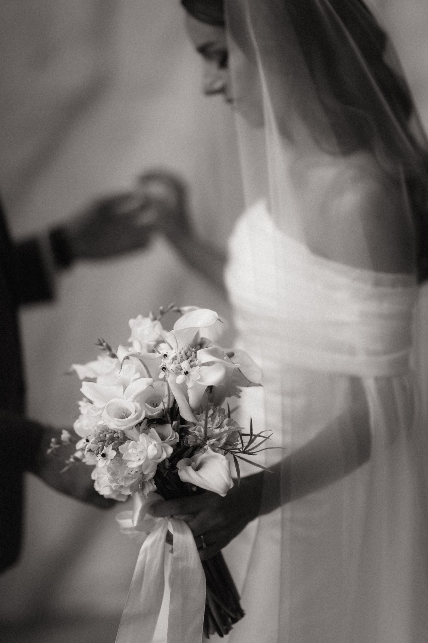 Black and white photo of an elegant bridal bouquet with white flowers and flowing ribbons.
