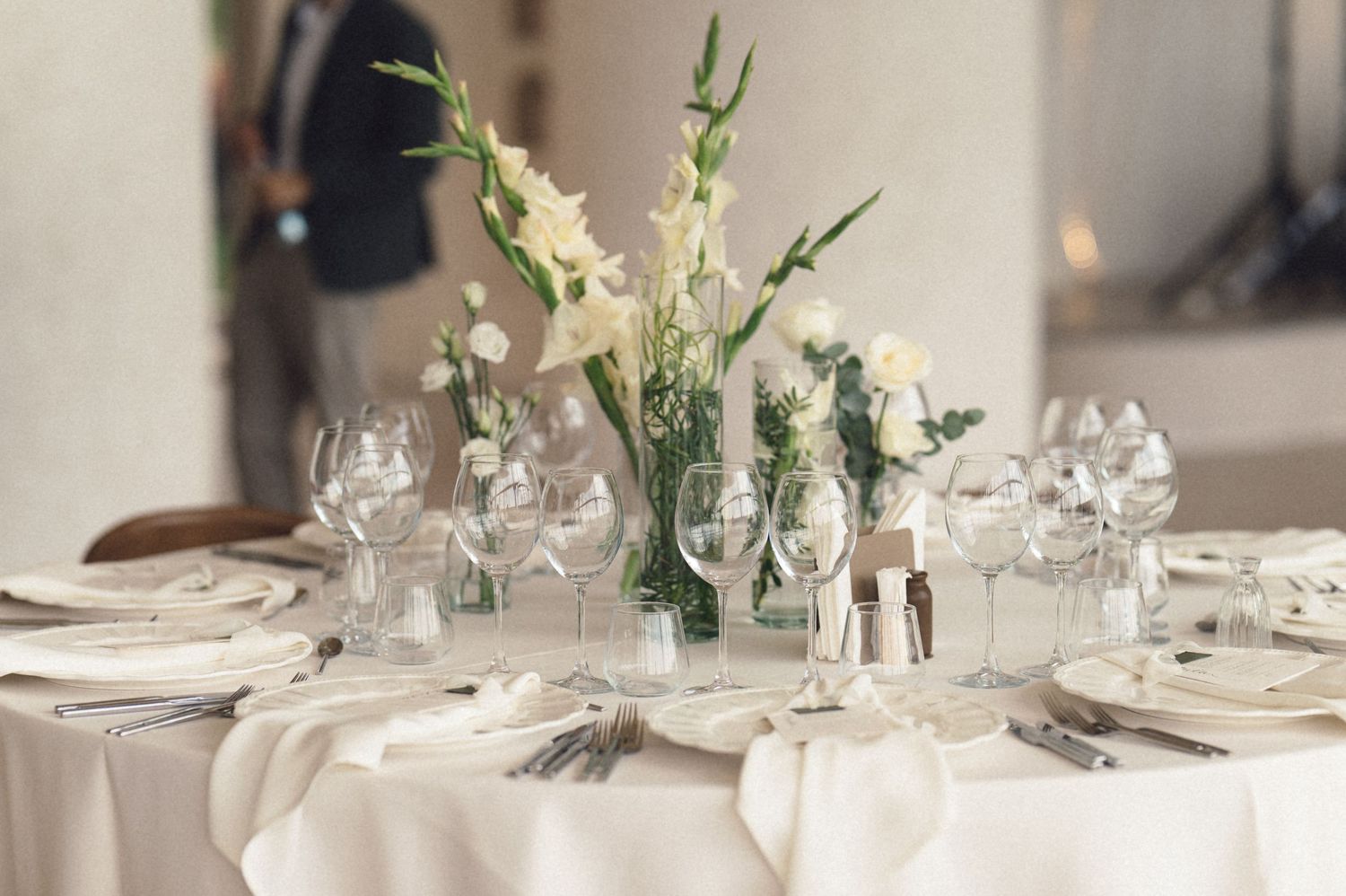 Elegant table settings with white linens, crystal glassware, and delicate floral centerpieces create a sophisticated dining atmosphere.