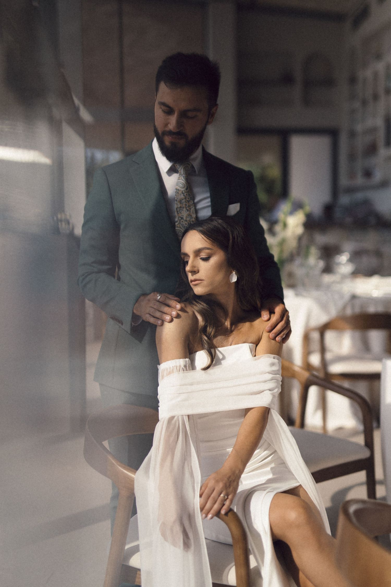 A romantic couple shares an intimate moment in soft lighting, with the woman wearing a white off-shoulder dress.