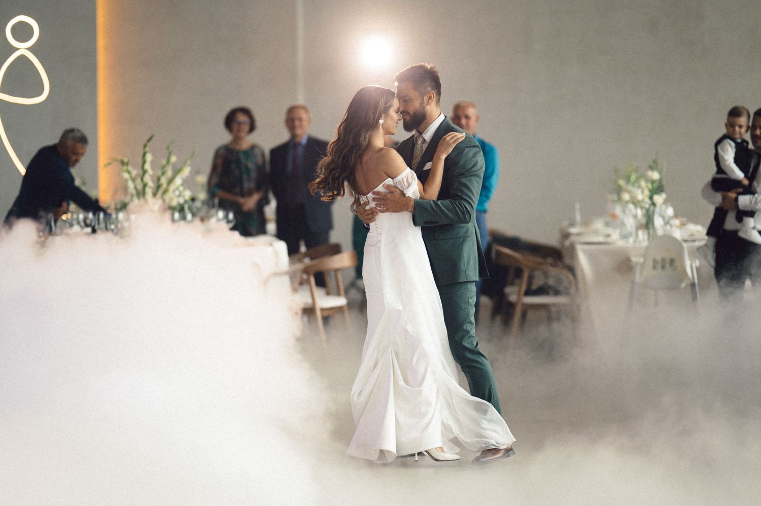 Couples dance together in an elegant ballroom filled with atmospheric fog and soft lighting.