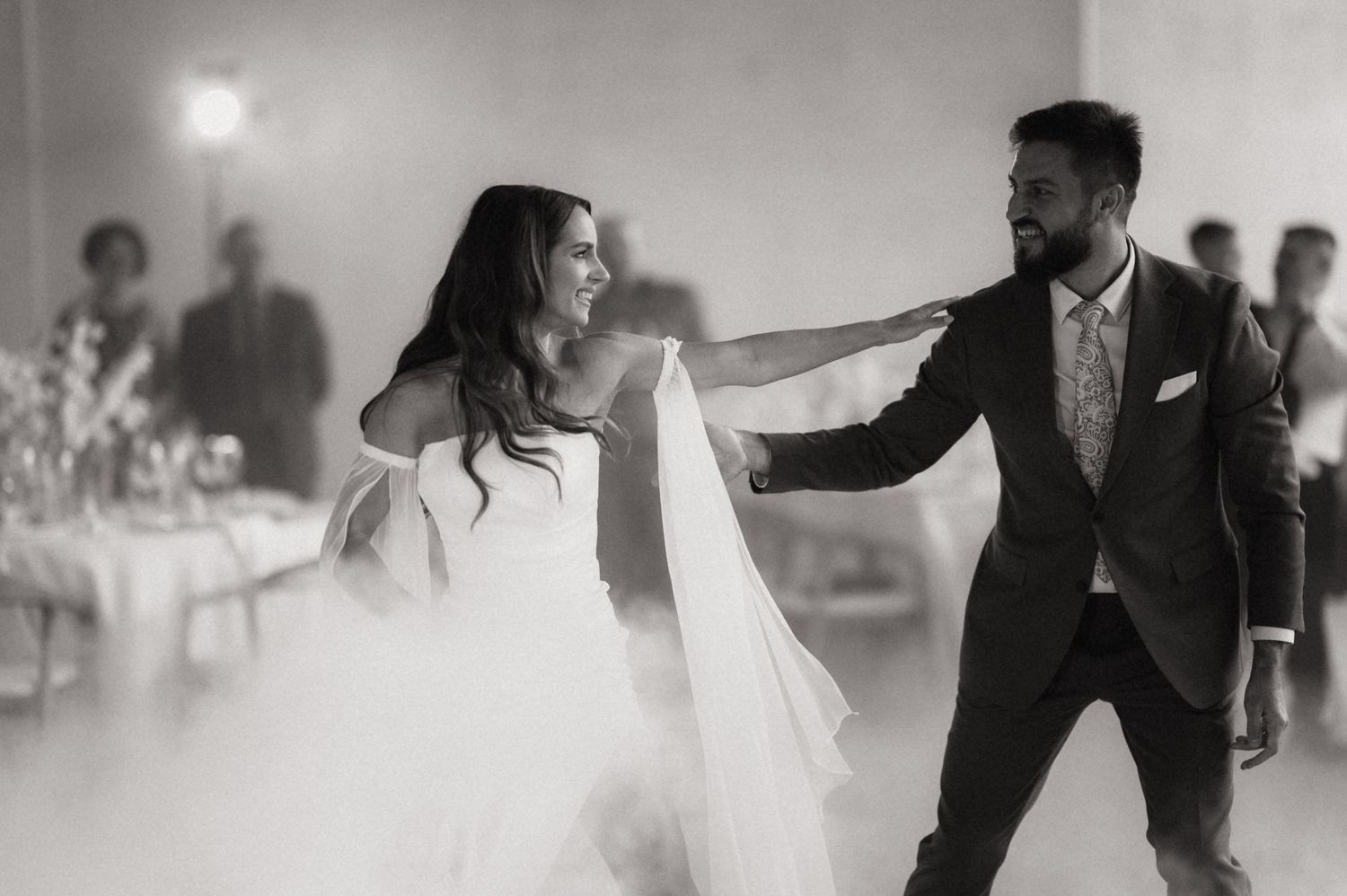 Wedding couples twirl and dance gracefully in a dreamy, fog-filled reception venue.