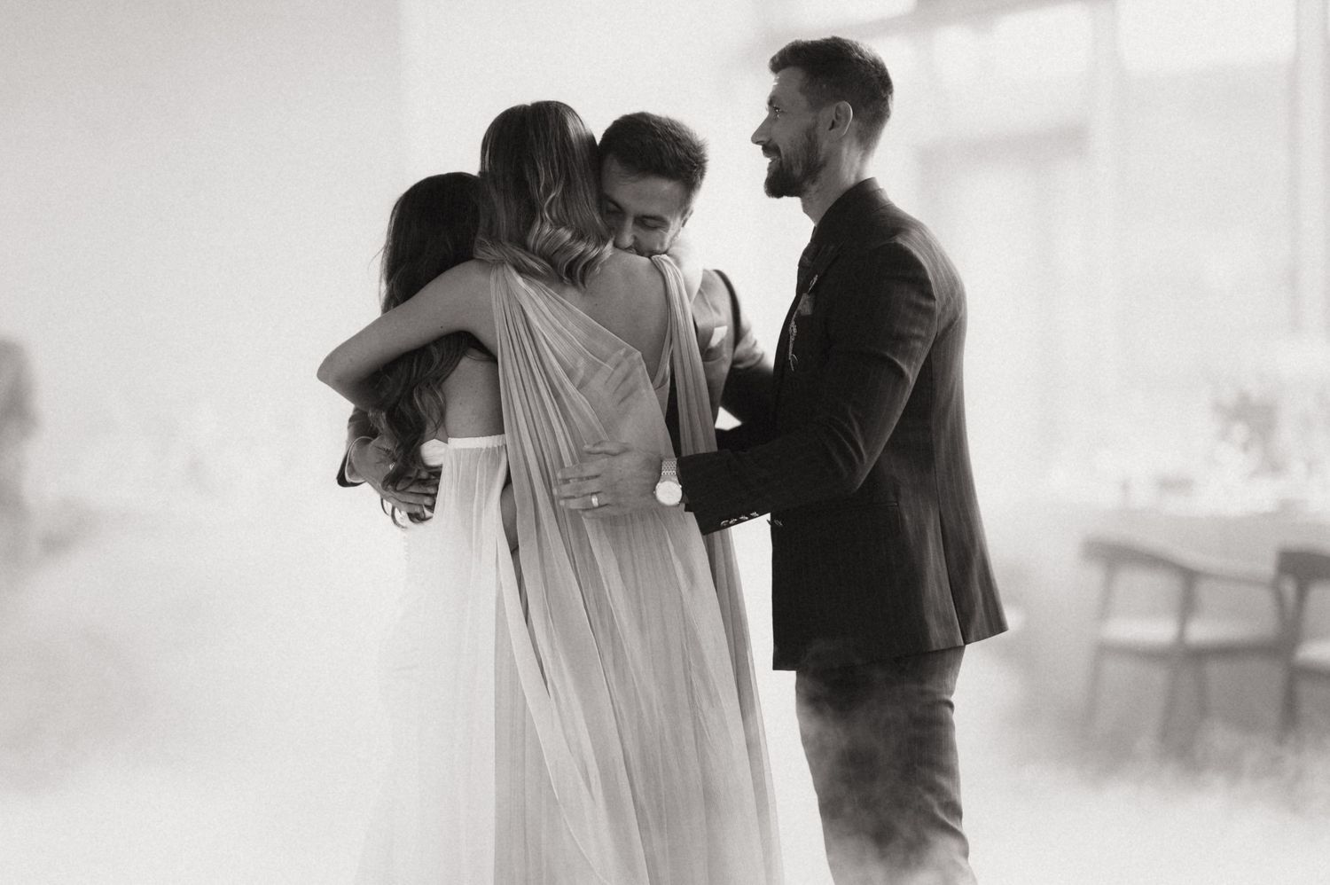 A couple shares an intimate moment during their first dance at a wedding reception in black and white.