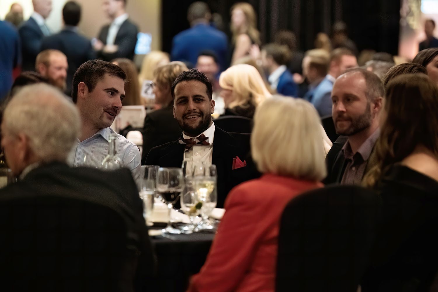 Guests seated at a round table during a formal dinner event, engaged in conversation.