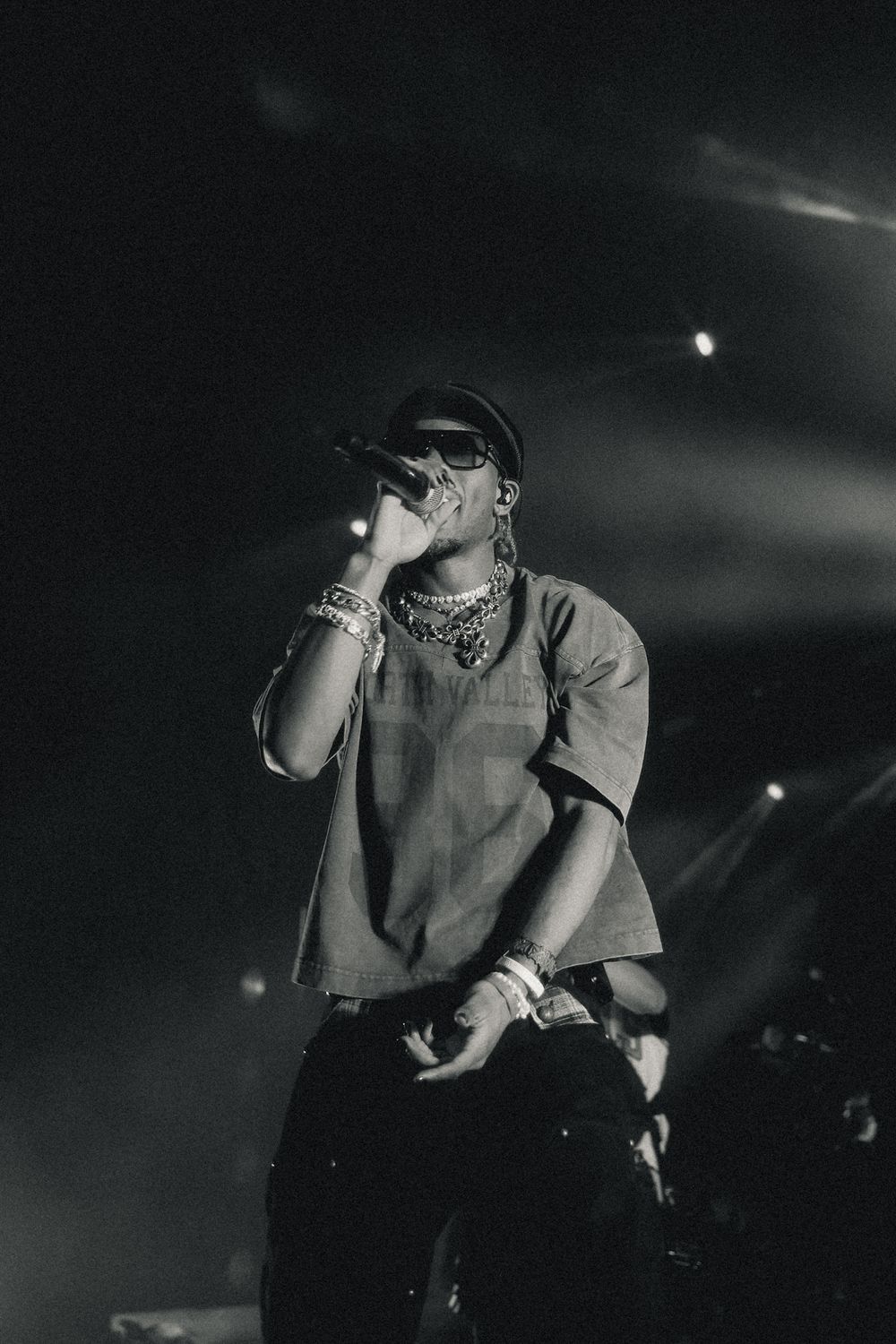 Dramatic black and white concert photo showing silhouetted performer on dark stage.
