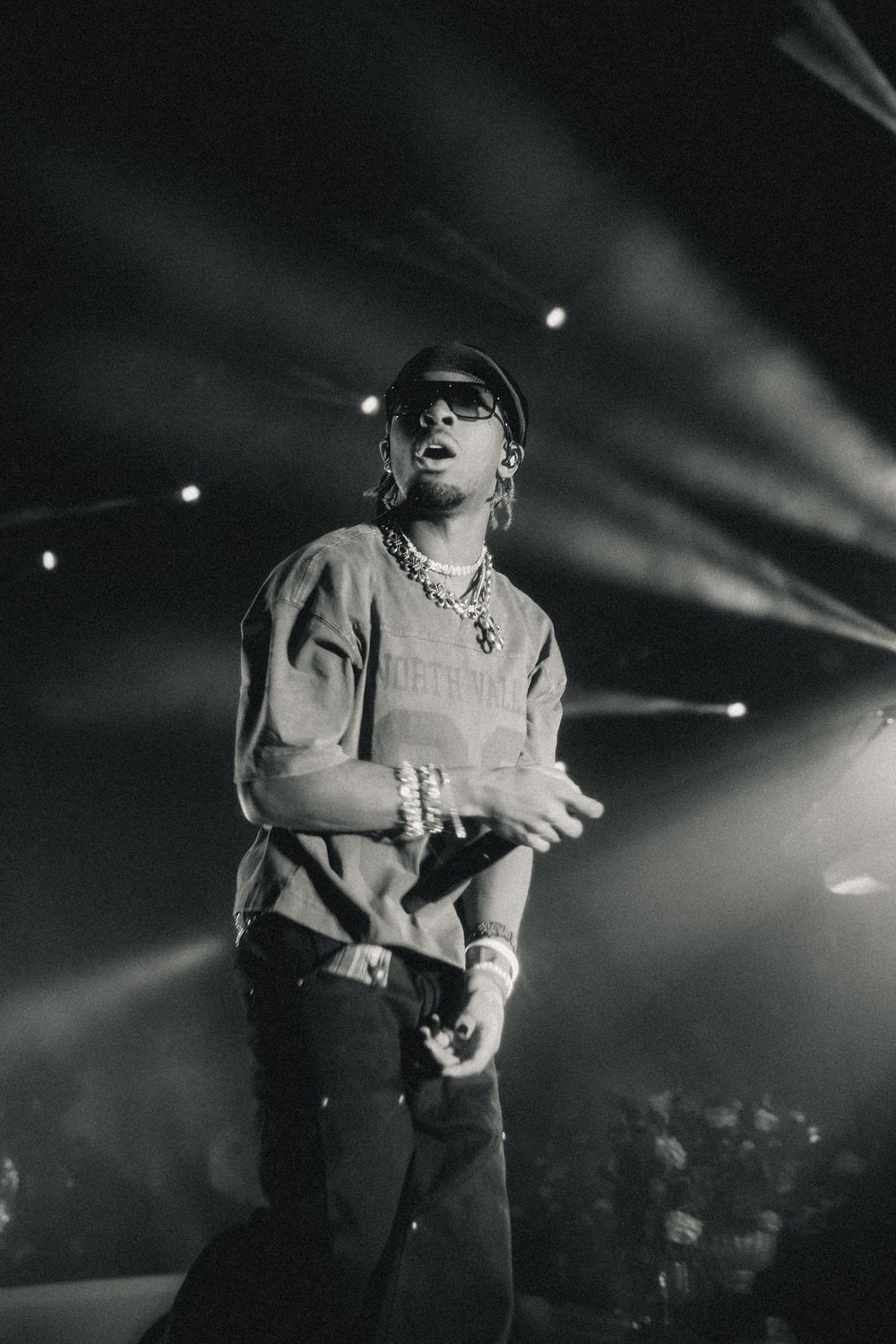 Black and white photo of concert performer in casual attire on dimly lit stage.