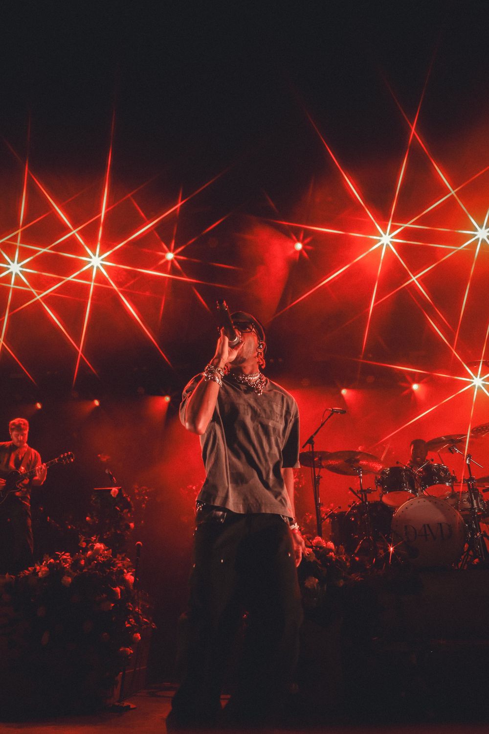 Concert stage lit with dramatic red lighting and star-like effects during live performance.