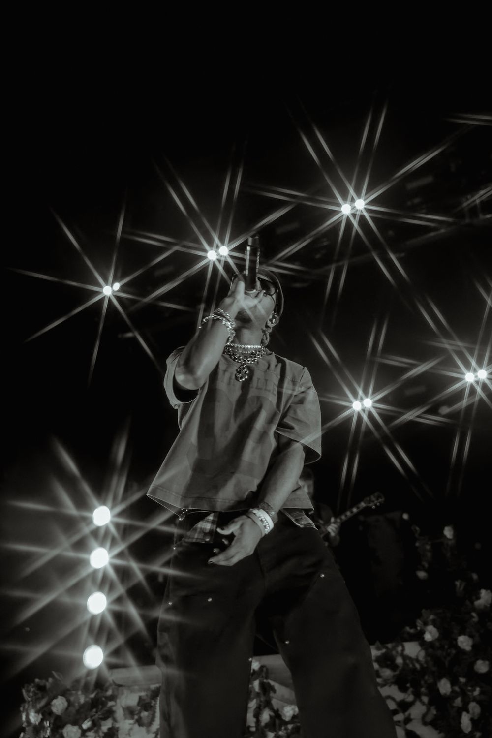 Concert performer captured in dramatic black and white with starburst lighting effects above.