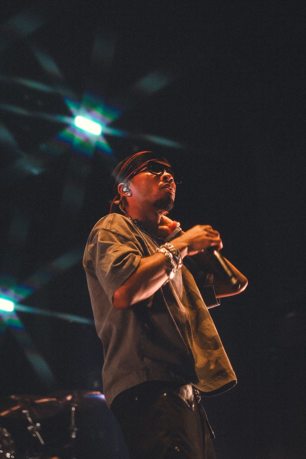 Hip hop performer energetically delivers lyrics on stage under moody blue lighting at concert venue.
