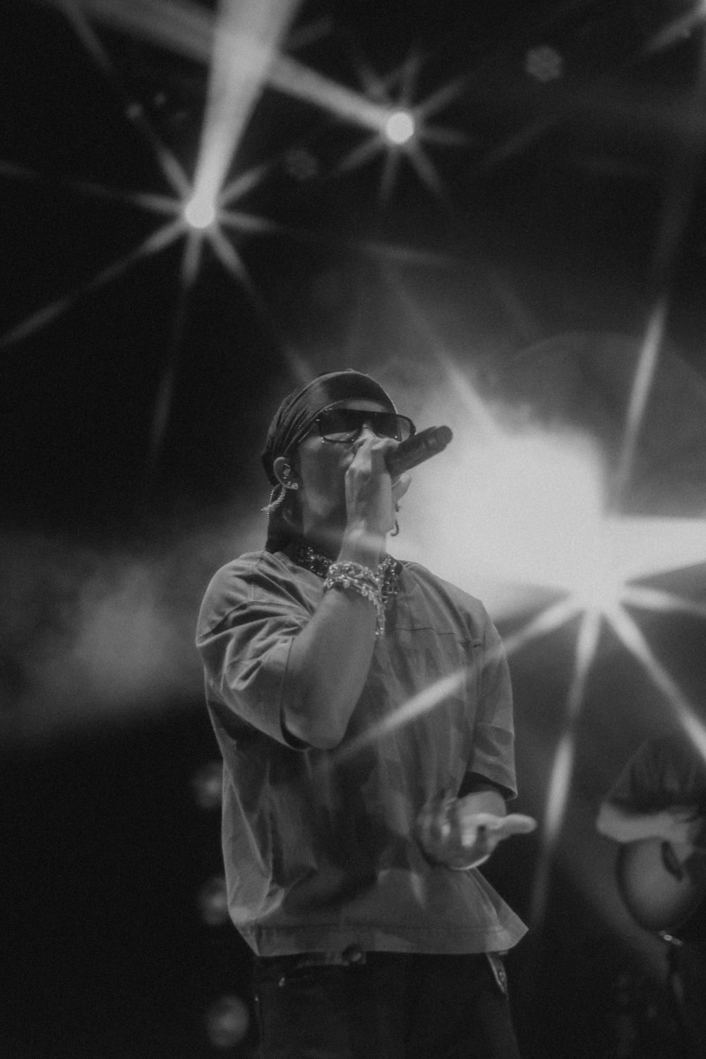 Black and white concert photo with performer silhouetted against starburst stage lights.