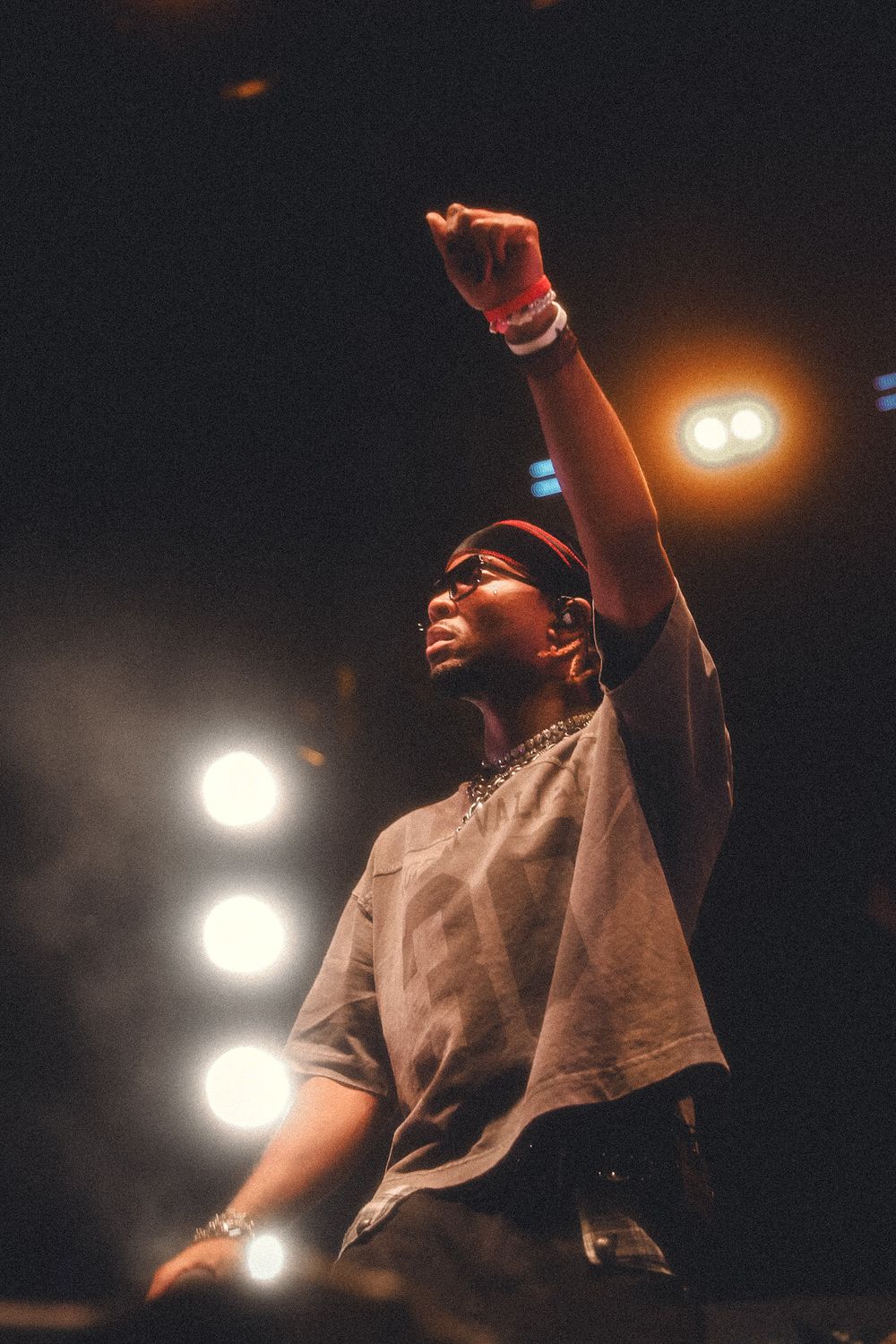 Concert artist raises arm during passionate performance under warm spotlights.
