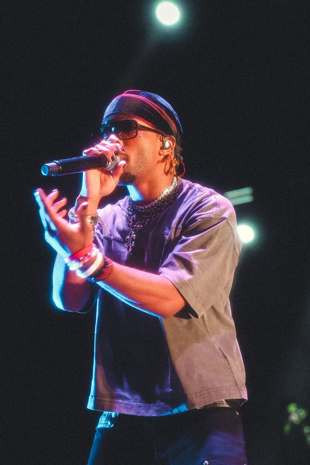 Performer in casual attire delivers energetic vocals under purple stage lighting.