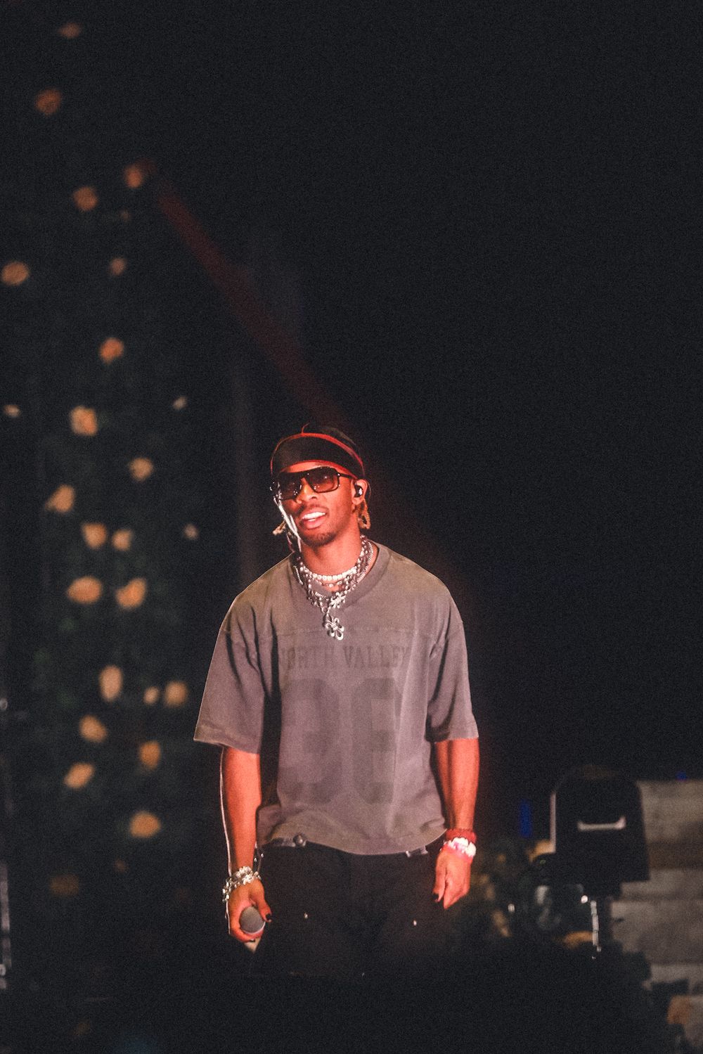 Artist in gray t-shirt performs on dimly lit stage with bokeh lighting effects in background.