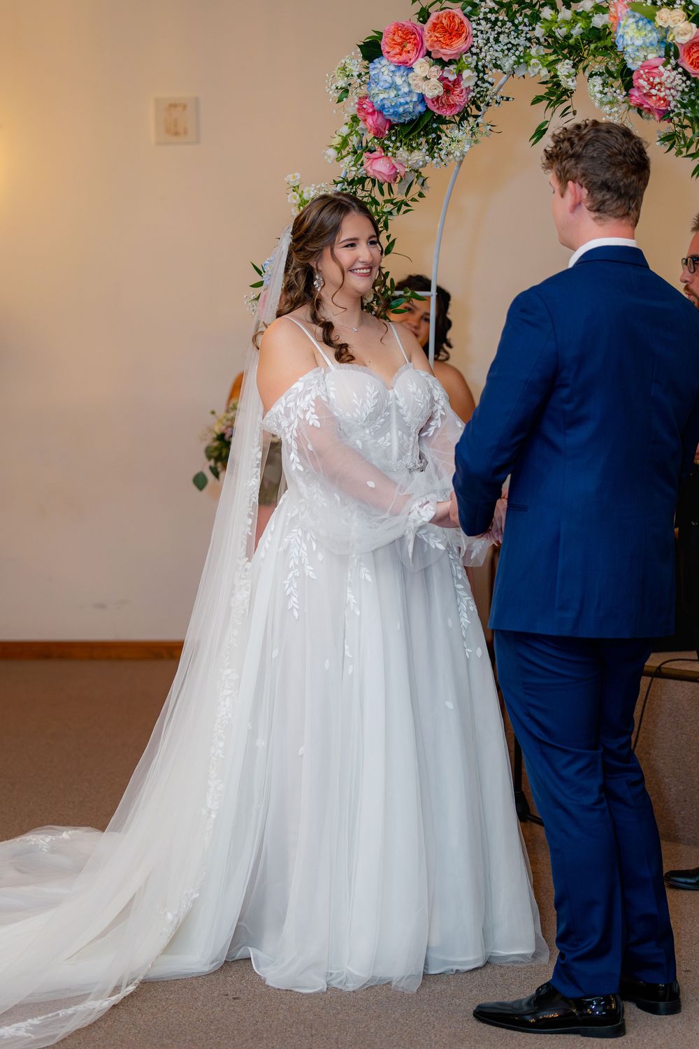A sequence of wedding photos showing a couple in traditional white gown and navy suit from behind during their ceremony.