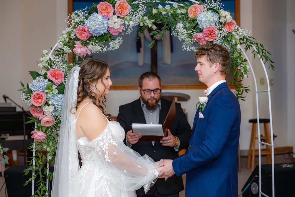 Wedding ceremony setup with a beautiful floral arch featuring pink and blue roses with greenery.