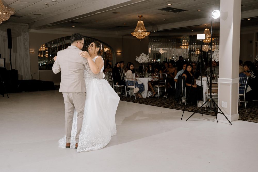 A spacious wedding reception hall with white decor, columns and ambient lighting creates an elegant atmosphere.
