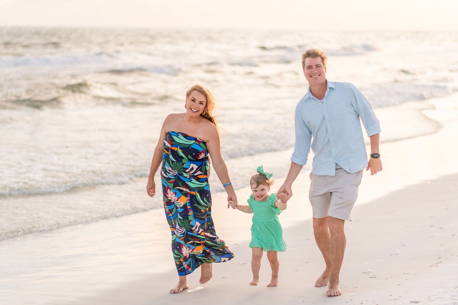 Family walking hand in hand along a pristine white sand beach at sunset.
