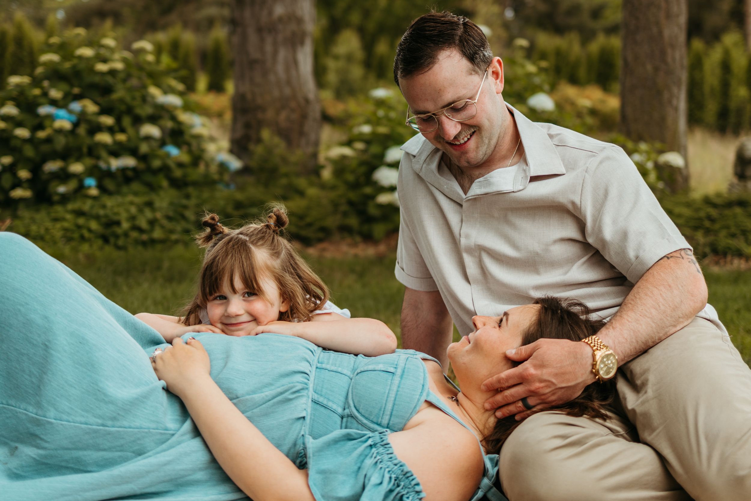 Family lying together on a turquoise couch sharing tender moments during a lifestyle photoshoot.