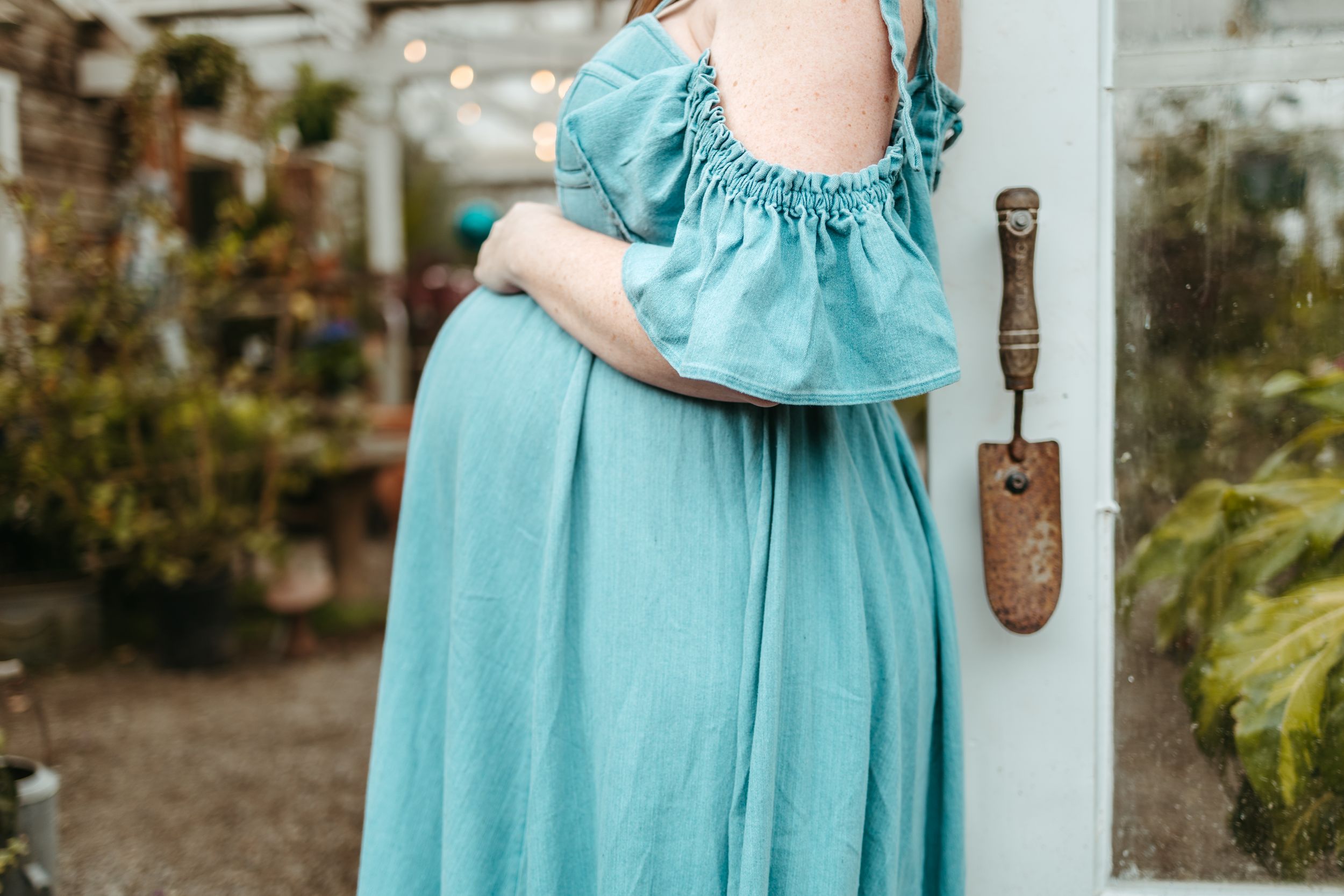 Close-up details of a light blue dress with ruffled fabric shown against a greenhouse backdrop.