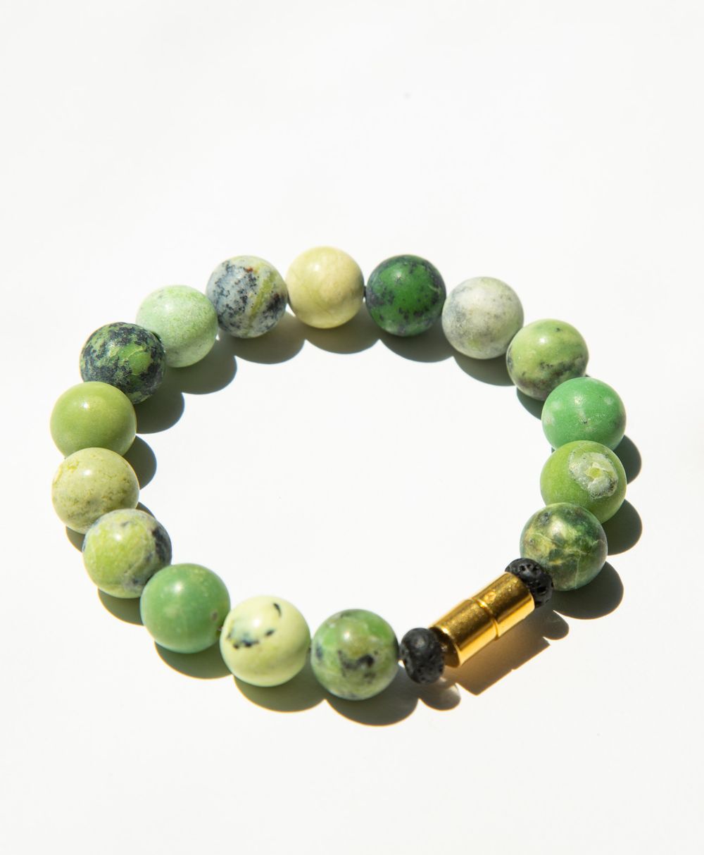 Green and yellow turquoise beads arranged in a curved line with gold-colored metal accents.