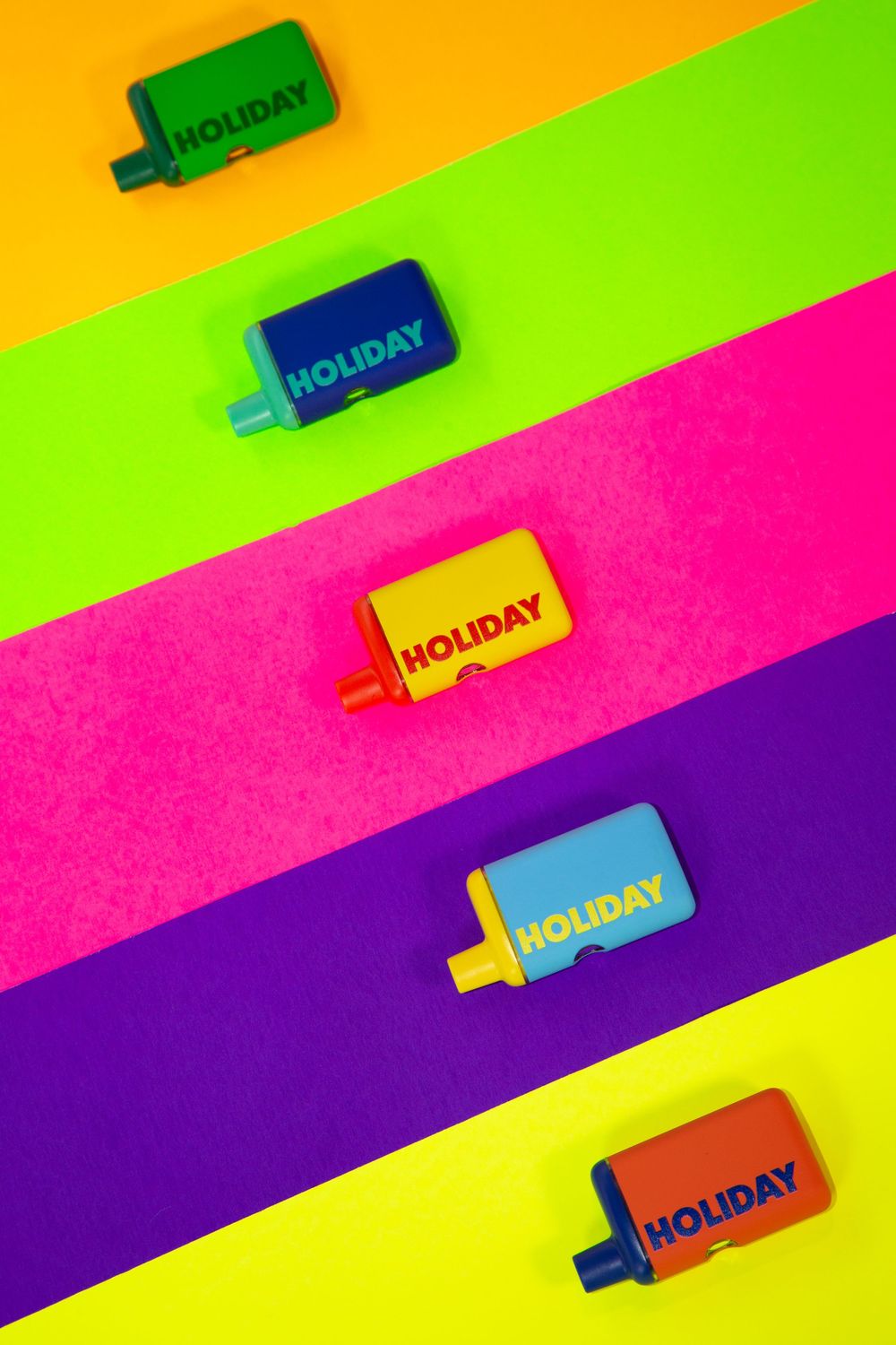 Colorful holiday text stamps arranged diagonally on vibrant neon striped background of yellow, green, pink and purple.