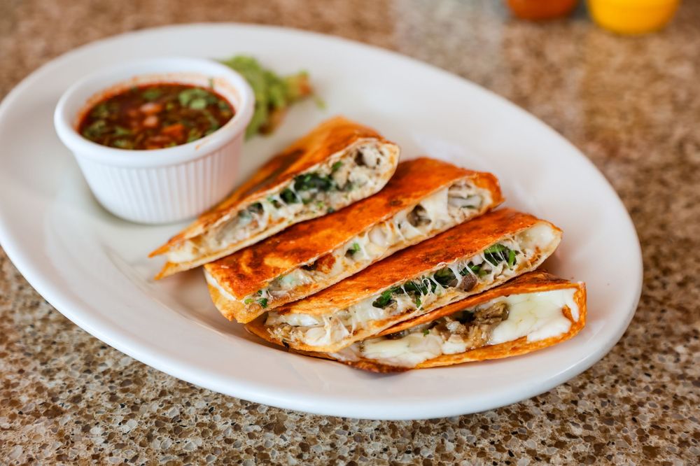 Golden quesadillas filled with chicken, cheese, and spinach, served with fresh salsa dipping sauce on a white plate.