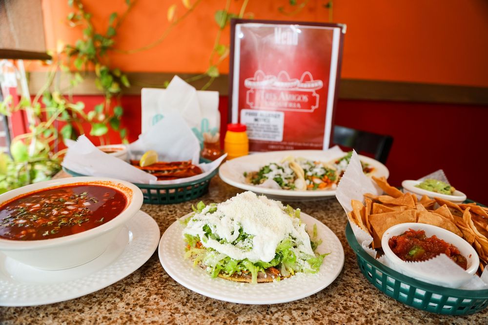 Mexican restaurant table spread with tacos, chips, salsa, and red soup on a granite countertop.