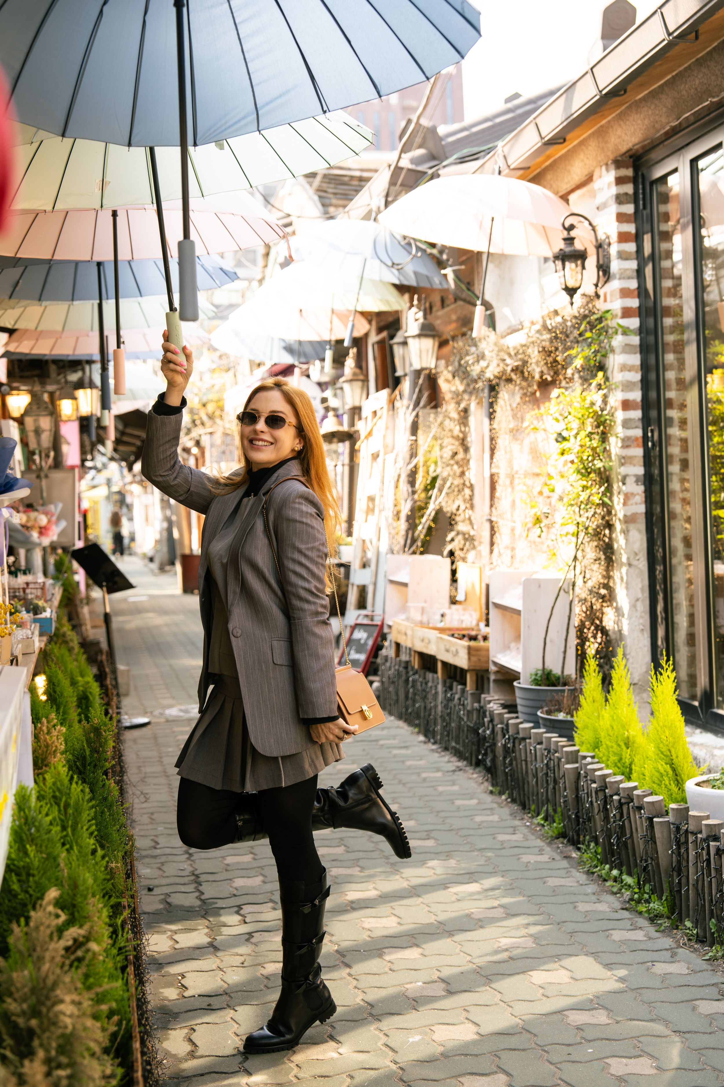Person walking with a blue parasol along a traditional stone-paved street with shops.