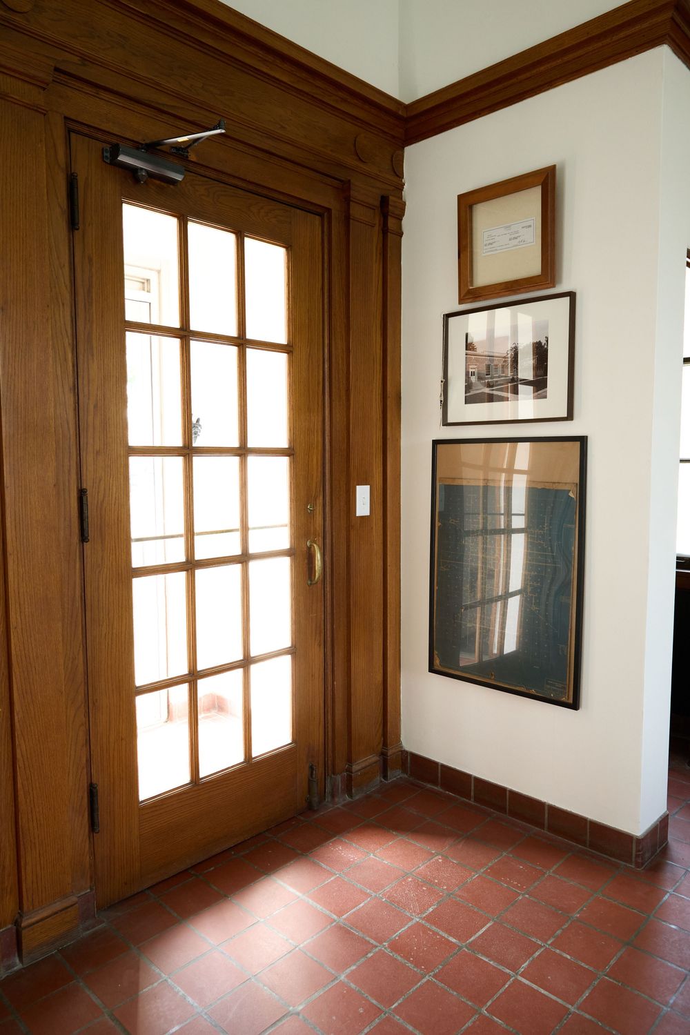 Interior entryway with terra cotta tile floor and dark wood trim featuring large windows.