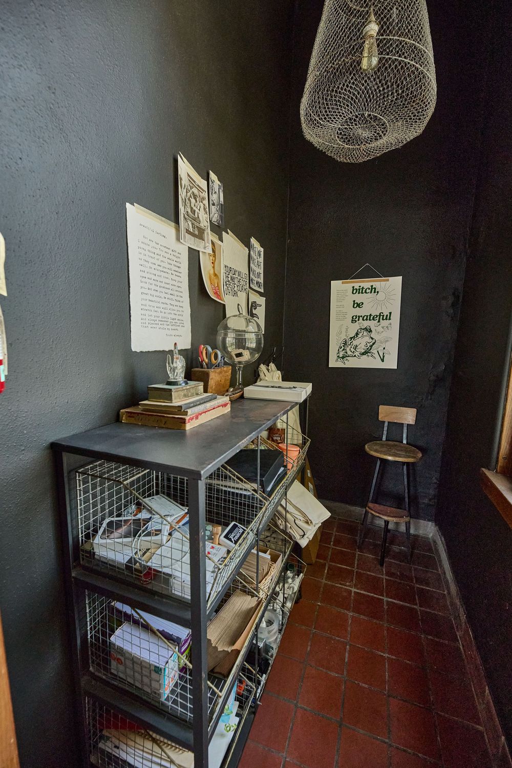 Dark room with terracotta floors featuring wire storage shelves and hanging pendant lights.