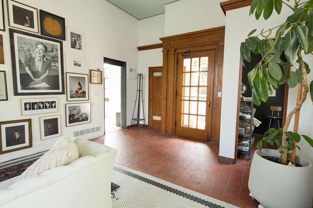 Minimalist white room with wooden trim windows and gallery wall of black and white photographs.