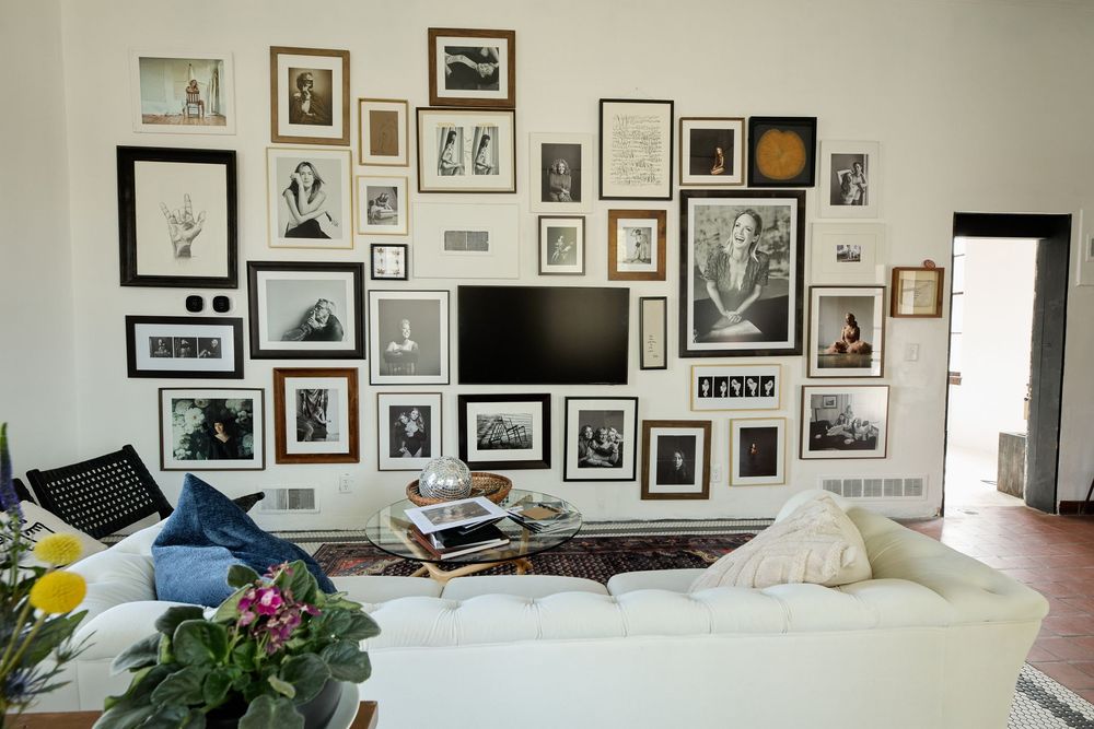 Long white wall decorated with an extensive collection of framed photographs and artwork.