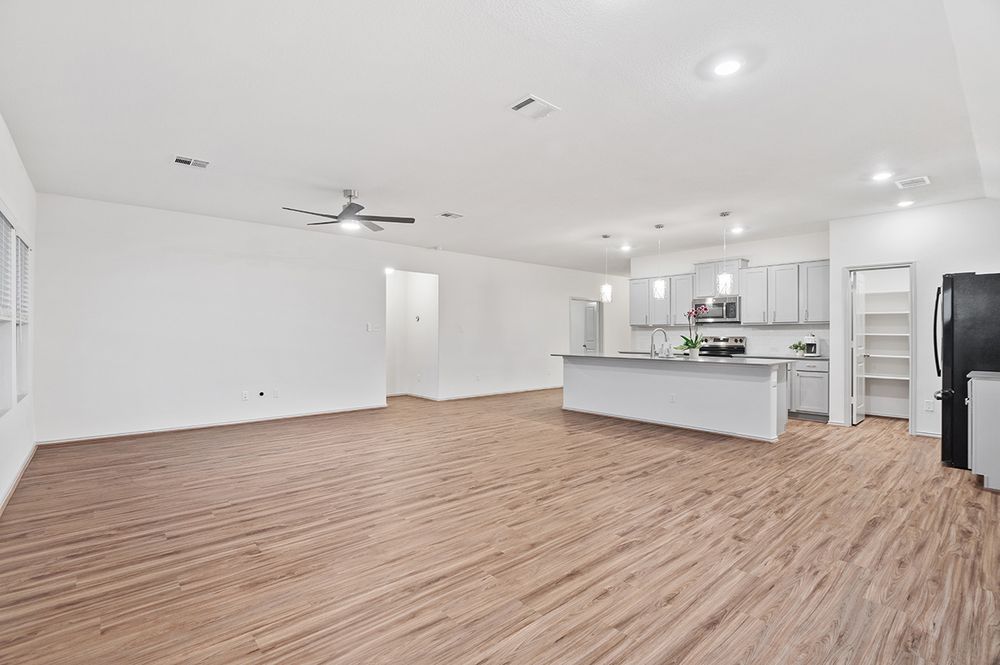 Large empty white modern space with hardwood floors, ceiling fan, and recessed lighting suitable for office or studio.