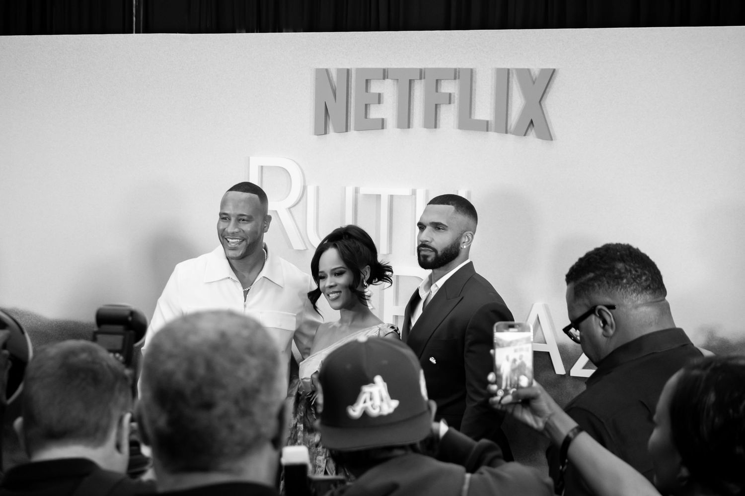 Netflix promotional event with attendees and white Netflix logo on display wall.