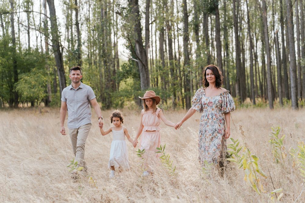 During a family photoshoot in Sydney a family walking together through a sunlit forest of tall pine trees in casual attire