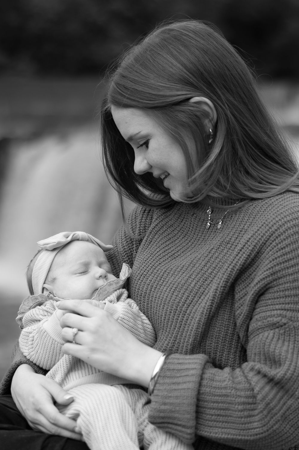 A tender black and white photo series showing a parent in a sweater cradling and bonding with their newborn baby.
