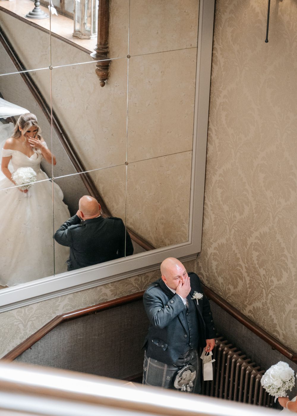 A wedding photographer captures moments on an elegant staircase with ornate details.