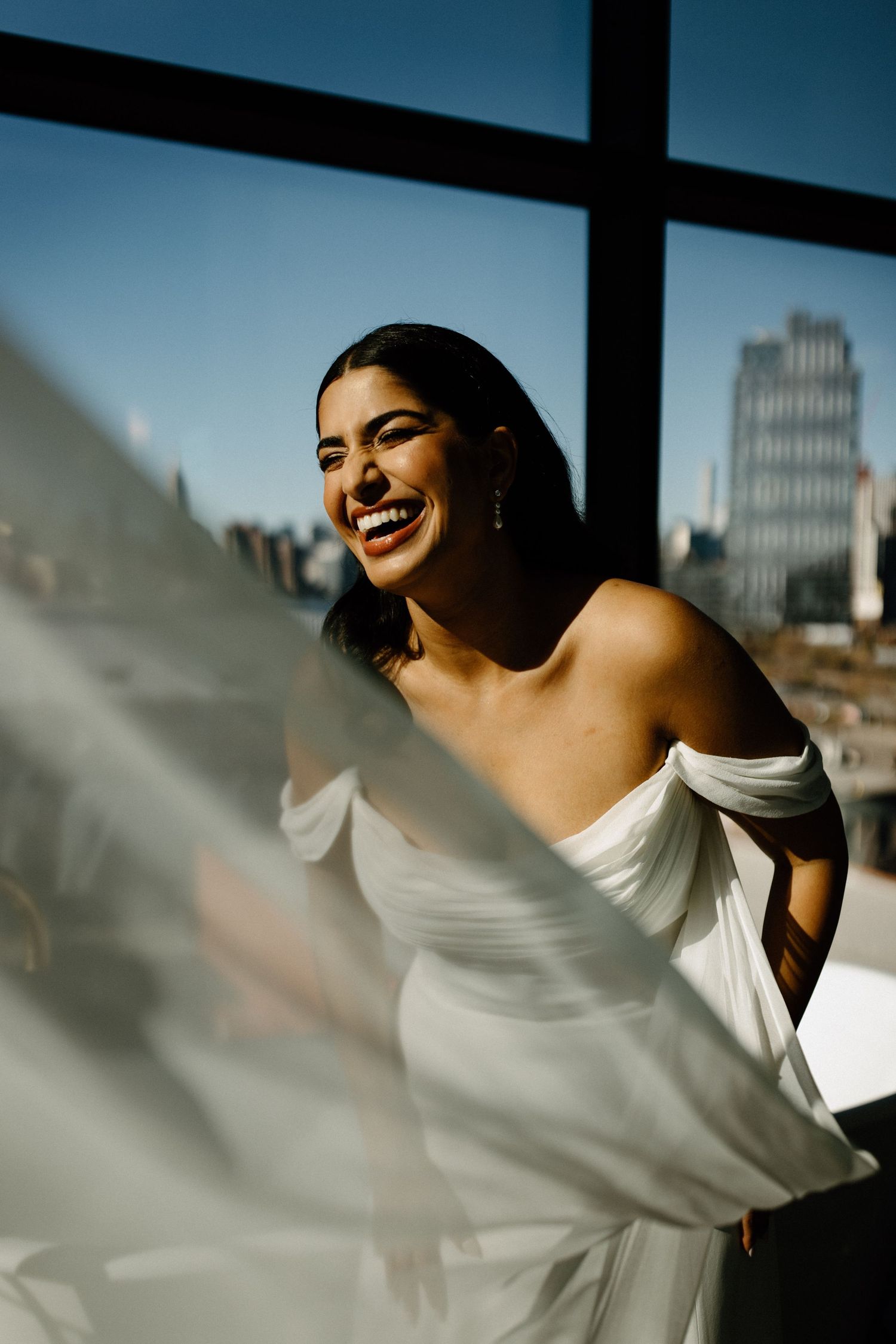 Flowing white fabric catches sunlight against an urban skyline backdrop.